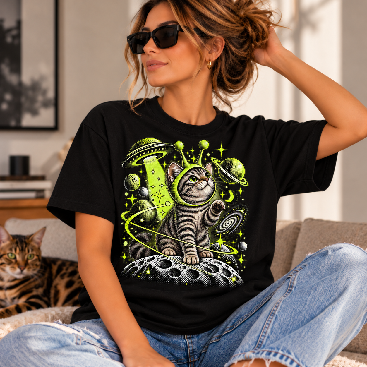 Cosmic cat UFO graphic T-shirt featuring a tabby cat on the moon with lime-green planets and stars